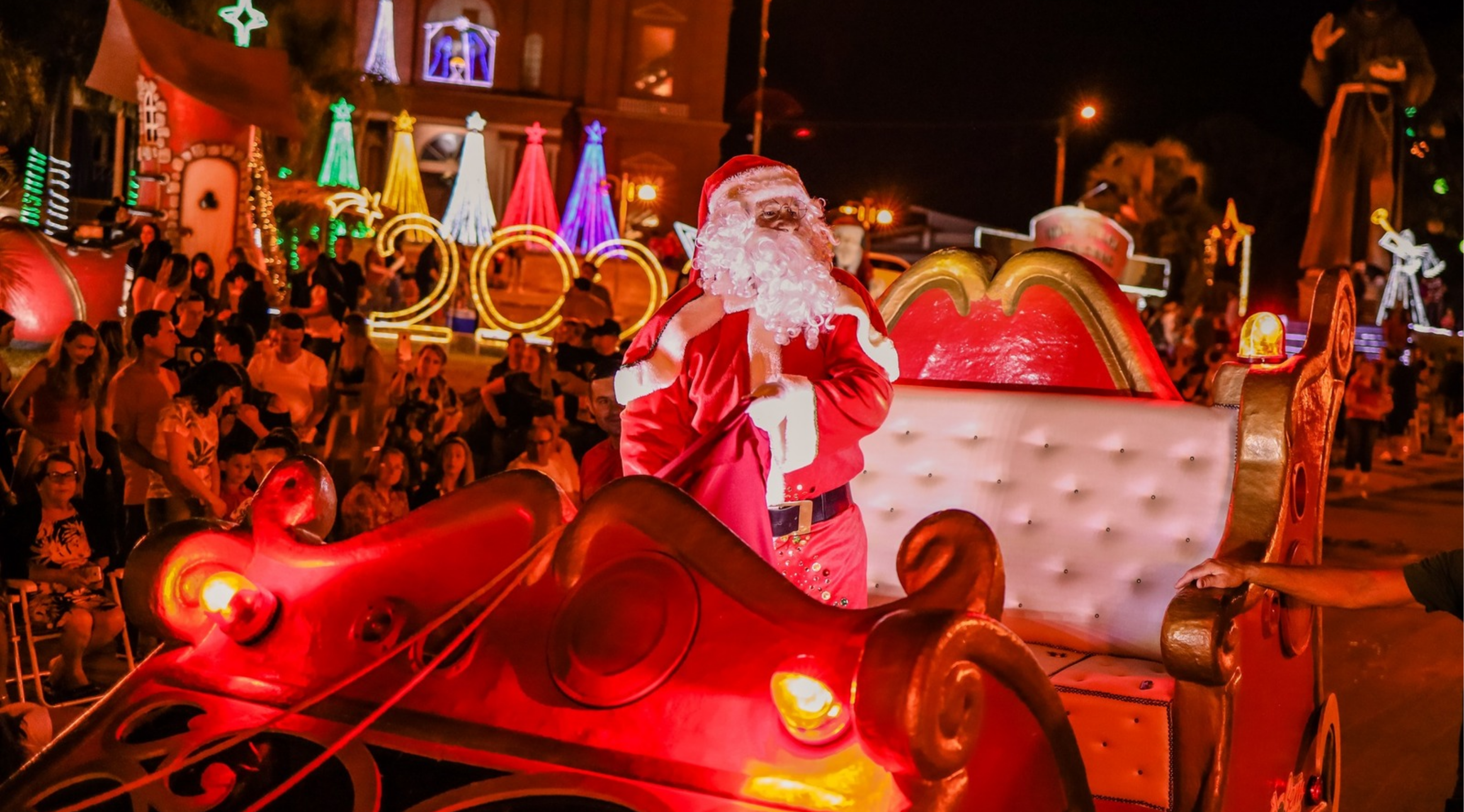 Chegada do Papai Noel em um trenó iluminado durante evento natalino